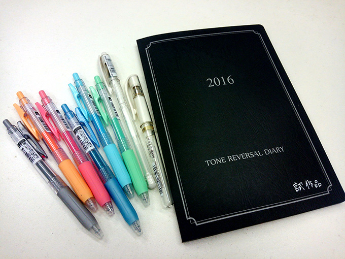 写真：TONE REVERSAL DIARYの表紙と、手帳に書きやすい白やパステルカラーのインクペン。